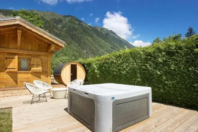 a outdoor deck with a hot tub and a house at Chalet Béchar Le Magnifique- Garden - Sauna & Jacuzzi in Les Houches