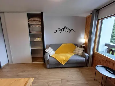 a living room with a couch with a yellow blanket at Studio cosy de 23 m2 à la montagne in Samoëns
