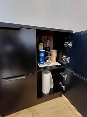a cupboard with a bottle of wine and toilet paper at Studio cosy de 23 m2 à la montagne in Samoëns