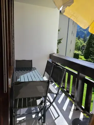 a balcony with a chair and an umbrella at Studio cosy de 23 m2 à la montagne in Samoëns