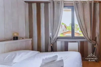 a bedroom with a bed in front of a window at Appartements 2 pièces vue Mont-Joly à 2 pas Tramway Mont-Blanc in Saint-Gervais-les-Bains