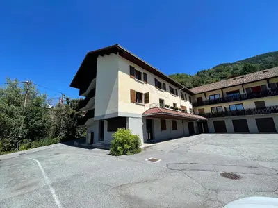 a building with a parking lot in front of it at Appartements 2 pièces vue Mont-Joly à 2 pas Tramway Mont-Blanc in Saint-Gervais-les-Bains