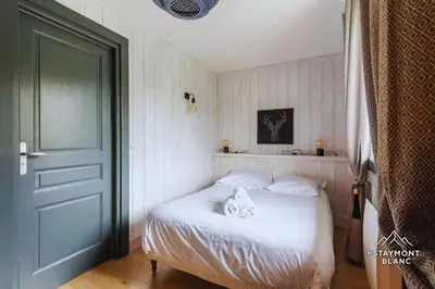 a bedroom with a bed with white sheets and a door at Appartements 2 pièces vue Mont-Joly à 2 pas Tramway Mont-Blanc in Saint-Gervais-les-Bains