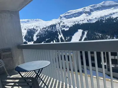 a chair and a table on a balcony with a snow covered mountain at Appart 6 personnes, balcon plein sud in Flaine