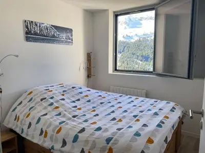 a bed in a bedroom with a large window at Appart 6 personnes, balcon plein sud in Flaine