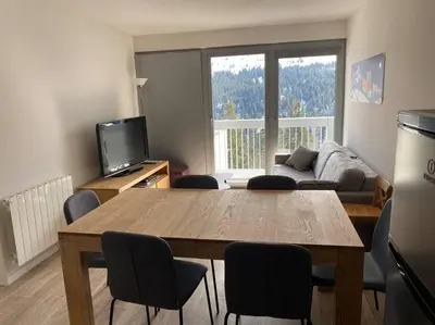 a living room with a table and chairs and a couch at Appart 6 personnes, balcon plein sud in Flaine