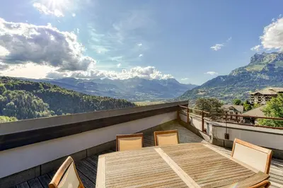 a wooden table and chairs on a balcony with mountains at Les Terrasses de Bel Alp in Saint-Gervais-les-Bains