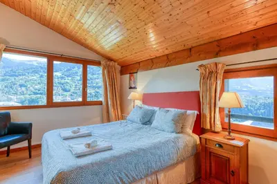 a bedroom with a bed and a chair and windows at Les Terrasses de Bel Alp in Saint-Gervais-les-Bains