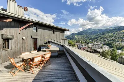 a balcony with a wooden table and chairs on a building at Les Terrasses de Bel Alp in Saint-Gervais-les-Bains