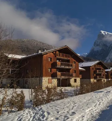 a building in the snow with a mountain in the background at Chardons Argentés in Samoëns