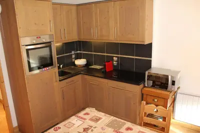 a small kitchen with wooden cabinets and a microwave at Chardons Argentés in Samoëns