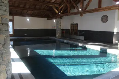 a swimming pool with blue water in a building at Chardons Argentés in Samoëns