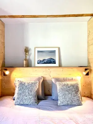 a bed with two pillows and a picture on the wall at Chalet familial Saint-Gervais in Saint-Gervais-les-Bains