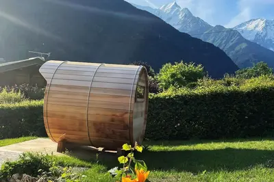 a wooden tub sitting in the grass with mountains in the background at Chalet familial Saint-Gervais in Saint-Gervais-les-Bains