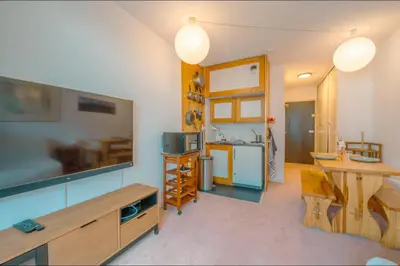 a living room with a kitchen with a table and a television at Chamonix Sud - Bâtiment Iris 374 - Happy Rentals in Chamonix-Mont-Blanc