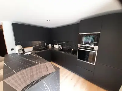 a kitchen with black cabinets and a counter top at Chalet Henriette by Brennus Chamonix in Chamonix-Mont-Blanc