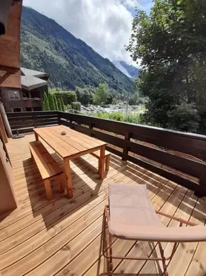 a wooden deck with a wooden table and chairs at Chalet Henriette by Brennus Chamonix in Chamonix-Mont-Blanc