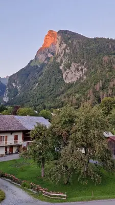 a view of a mountain with a house and a tree at Appartement Le Carlina 22B -MERCI DE LIRE TOUT ET disposition des chambres pour éviter une mauvaise note - Ce nest PAS un Hôtel - MINIMUM 5 nuits - sans le linge de maison - Vue sur le Criou - Sil y a de la place sur le parking, vous pouvez vous y garer in Samoëns