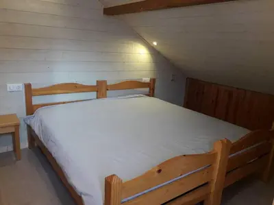 a large wooden bed in a small room at Appartement Le Carlina 22B -MERCI DE LIRE TOUT ET disposition des chambres pour éviter une mauvaise note - Ce nest PAS un Hôtel - MINIMUM 5 nuits - sans le linge de maison - Vue sur le Criou - Sil y a de la place sur le parking, vous pouvez vous y garer in Samoëns