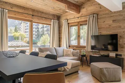 a living room with a couch and a tv at Chalet Marguerite by Brennus Chamonix in Chamonix-Mont-Blanc