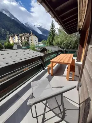 a wooden table and a chair on a roof at Chalet Marguerite by Brennus Chamonix in Chamonix-Mont-Blanc