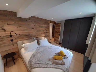 a bedroom with a large white bed with wooden walls at Chalet Marguerite by Brennus Chamonix in Chamonix-Mont-Blanc