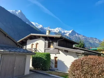 a white house with mountains in the background at Chalet Marguerite by Brennus Chamonix in Chamonix-Mont-Blanc