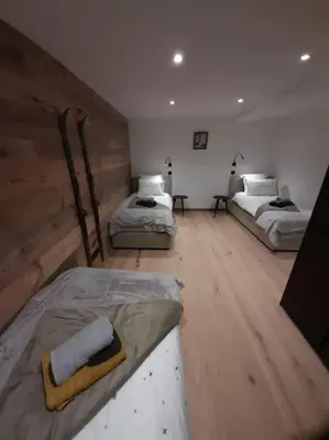 three beds in a room with wooden floors at Chalet Marguerite by Brennus Chamonix in Chamonix-Mont-Blanc