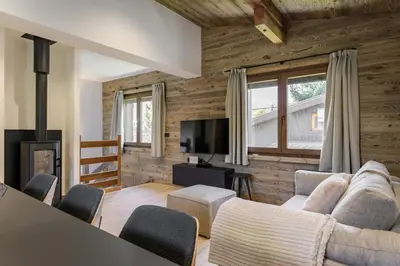 a living room with wooden walls and a couch and chairs at Chalet Claudia by Brennus Chamonix in Chamonix-Mont-Blanc