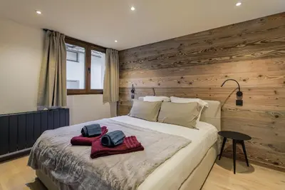 a bedroom with a large bed with wooden walls at Chalet Claudia by Brennus Chamonix in Chamonix-Mont-Blanc