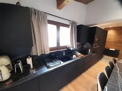 a kitchen with black cabinets and a sink and a window at Chalet Claudia by Brennus Chamonix in Chamonix-Mont-Blanc