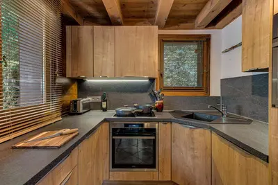 a kitchen with wooden cabinets and a sink at Chalet Blackbushe – Traditional Chalet - Alpes Travel – Sleeps 4-6 in Les Houches