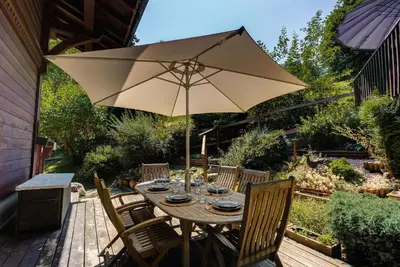 a wooden table with an umbrella on a patio at Chalet Blackbushe – Traditional Chalet - Alpes Travel – Sleeps 4-6 in Les Houches