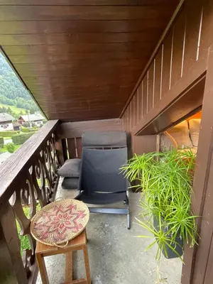 a balcony with a chair and a table and plants at Appartement 6 personnes les Contamines Montjoie in Les Contamines-Montjoie