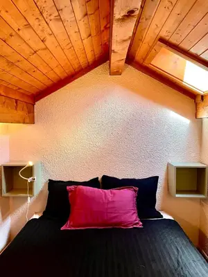 a bedroom with a black bed with a pink pillow at Appartement 6 personnes les Contamines Montjoie in Les Contamines-Montjoie