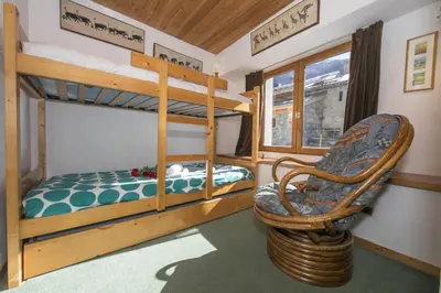 a bunk bed room with two bunk beds and a chair at Résidence Igloo 3 ski in-ski out - Happy Rentals in Le Tour