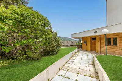 a house with a green lawn next to a building at Appartement Rochebrune De Megève 32 - Happy Rentals in Megève
