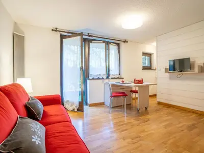 a living room with a red couch and a desk at Apartment Champraz-17 by Interhome in Chamonix-Mont-Blanc