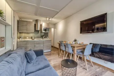 a living room and kitchen with a blue couch and a table at Aiguille du Grépon - Bright Apartment in the Heart of Chamonix in Chamonix-Mont-Blanc