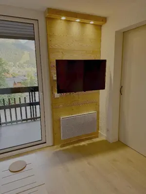 a room with a wall with a tv and a window at Les Airelles 406 in Les Carroz d'Araches
