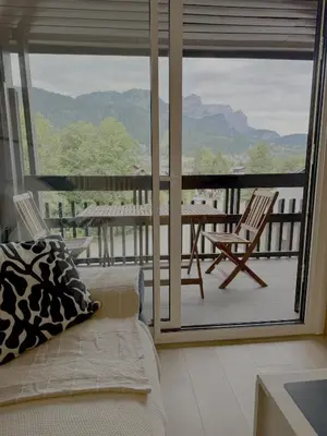 a living room with a couch and a balcony with a table and chairs at Les Airelles 406 in Les Carroz d'Araches