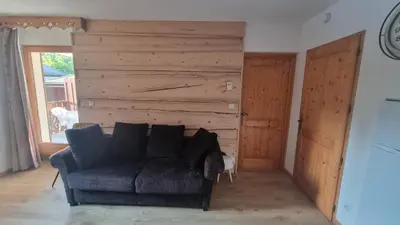 a living room with a couch and a wooden wall at Bel appartement avec piscine - Le Grand Tétras in Samoëns