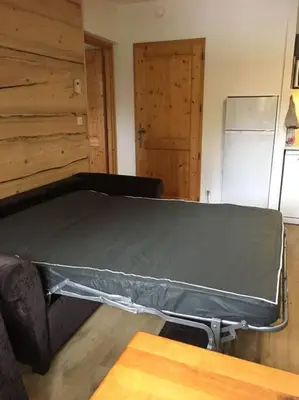a bed in a room with a table and a refrigerator at Bel appartement avec piscine - Le Grand Tétras in Samoëns