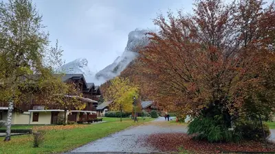 a street in a village with a mountain in the background at Bel appartement avec piscine - Le Grand Tétras in Samoëns