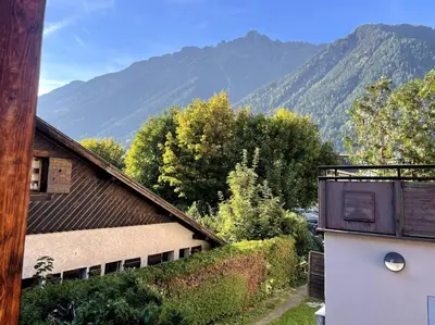 a view of a house with mountains in the background at Cosy appartement centre chamonix in Chamonix-Mont-Blanc