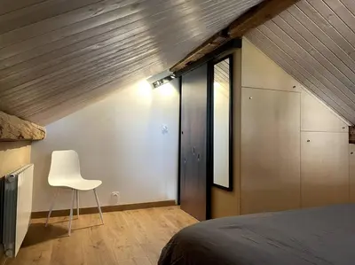 a bedroom with a bed and a white chair at Cosy appartement centre chamonix in Chamonix-Mont-Blanc