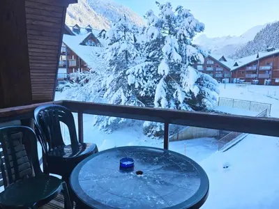 a table and chairs on a balcony with a snow covered tree at Aux Pieds des pistes en plein soleil in Les Contamines-Montjoie