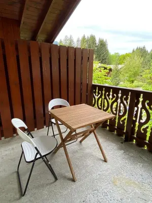 a wooden picnic table and two chairs on a balcony at Apt Sakura - Le Grand Tetras in Samoëns