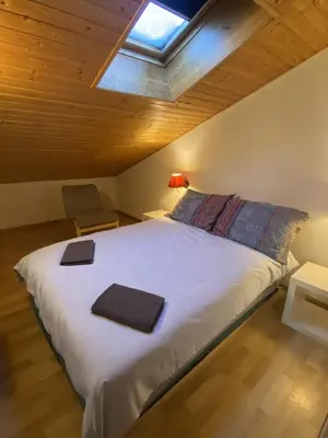 a bedroom with a large white bed with a skylight at Apt Sakura - Le Grand Tetras in Samoëns