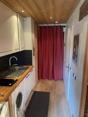 a kitchen with a red curtain and a washing machine at LOUE STUDIO MEGEVE in Megève